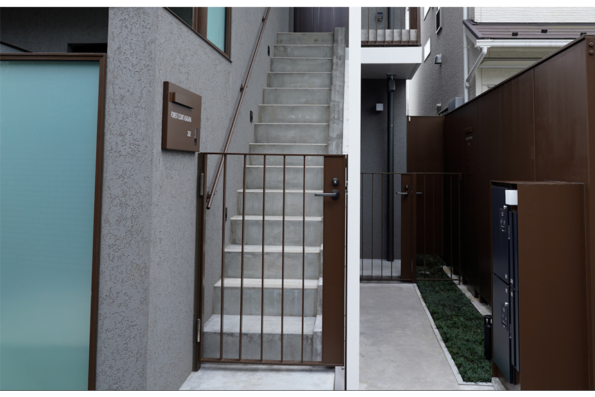 焦茶のスチール塀と玉龍の緑で誘いこむ1F玄関アプローチ